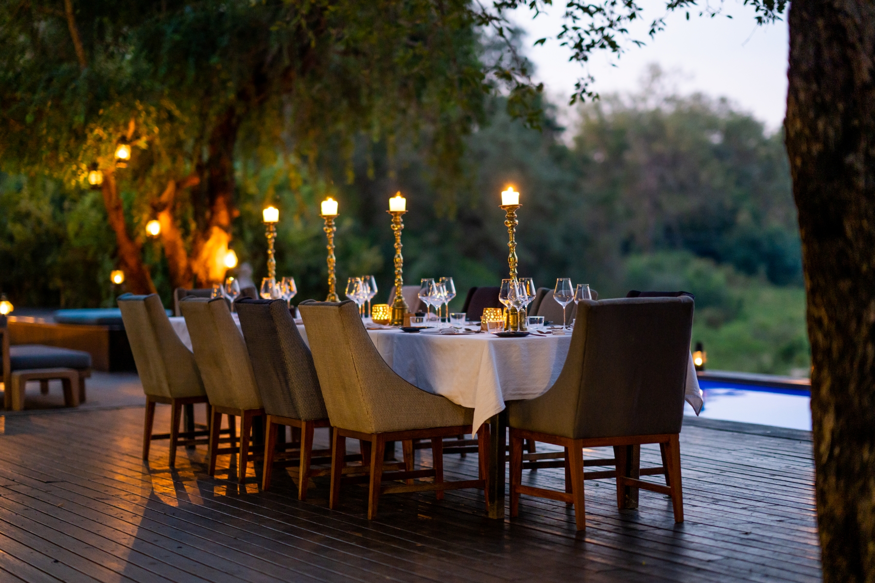 a-long-elegantly-set-dining-table-on-a-deck-lit-by-golden-candlelight.jpg