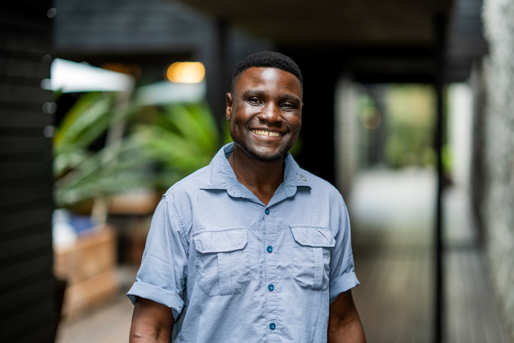 a-safari-guide-in-uniform-smiles-warmly-while-standing-in-a-lodge-walkway.jpg