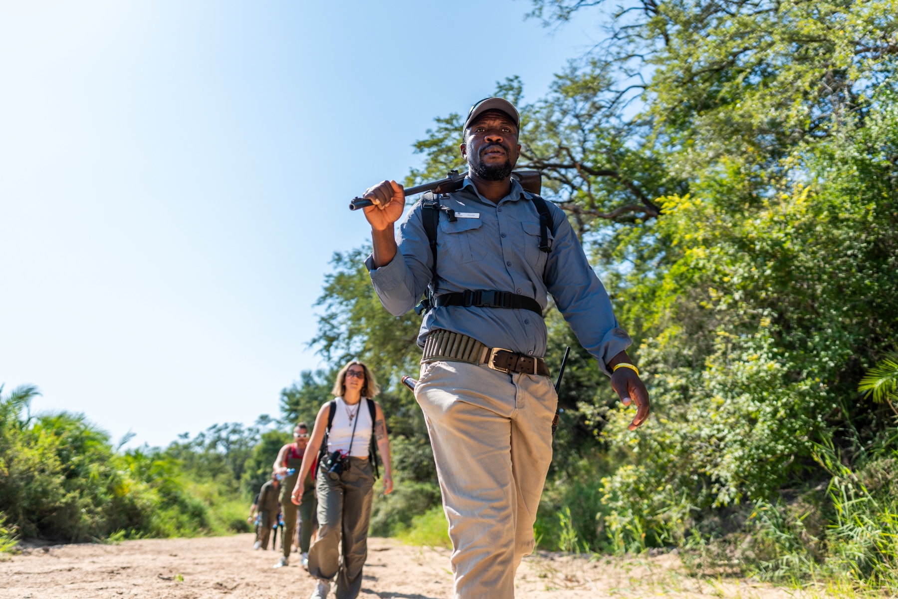 a-safari-guide-walks-purposefully-ahead-of-a-small-group-of-guests.jpg