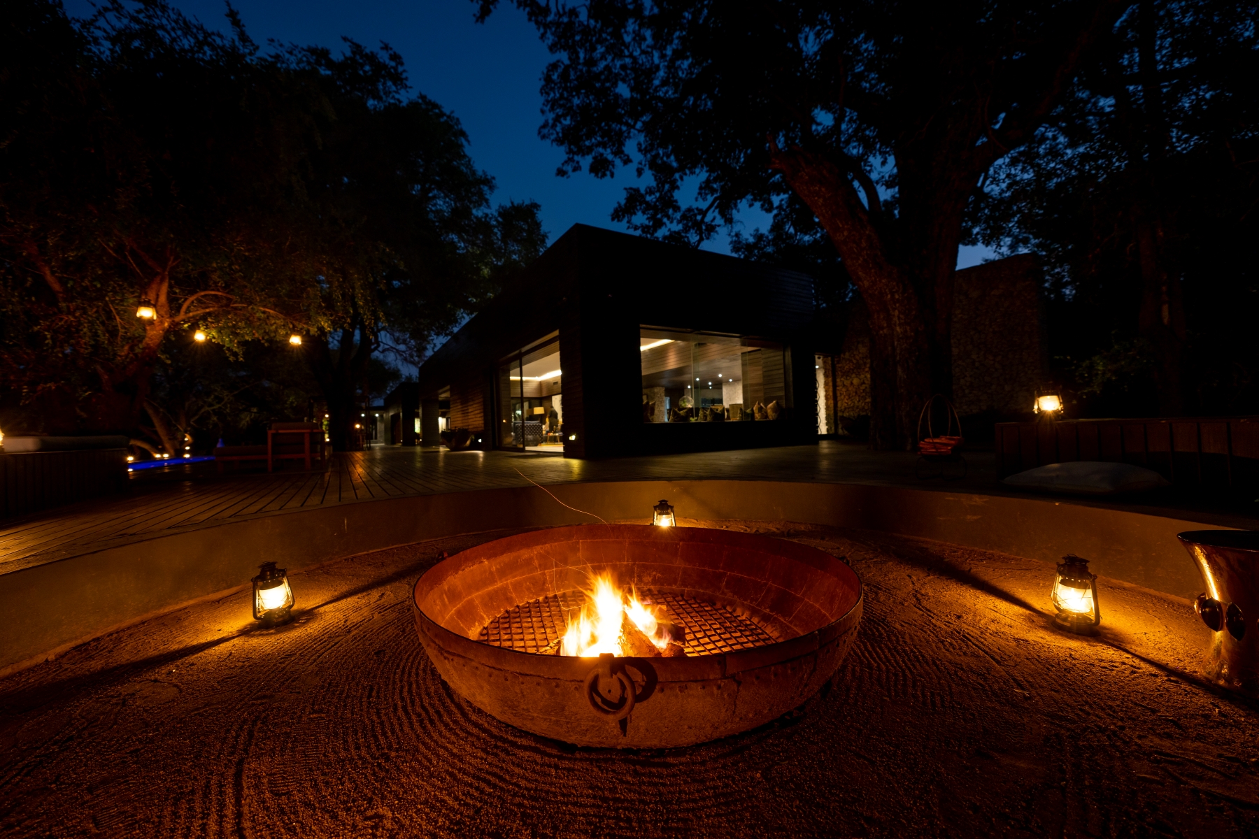 a-fire-pit-glows-at-night-surrounded-by-lanterns-and-modern-decking.jpg
