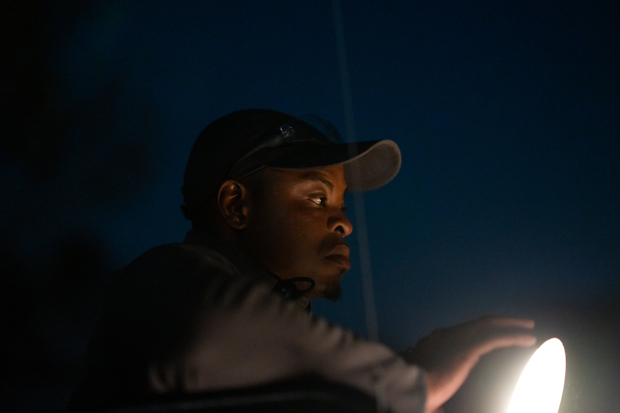 A safari guide expertly scanning the darkness with a spotlight, searching for nocturnal wildlife in the African bush.
